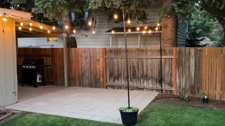 An outdoor patio area with outdoor lights hung on light poles.