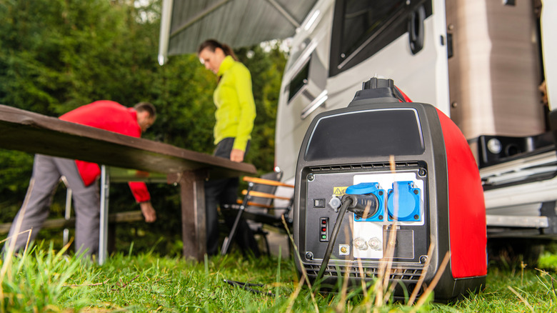man and woman camping in rv with generator hooked up