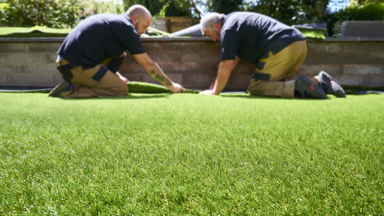 Two men laying artificial grass