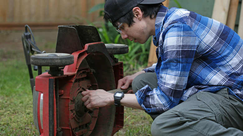 Man working on blade and spindle assembly, mower on its side