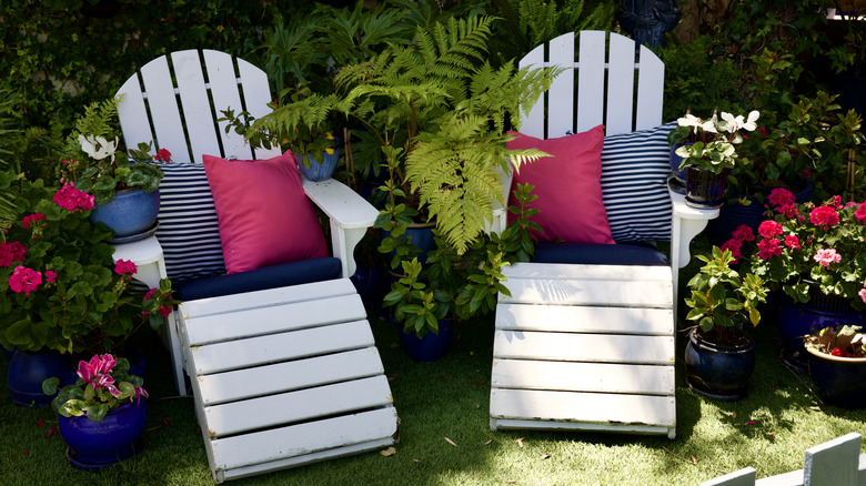Two white wooden recliners with pillows outside