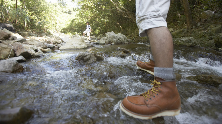 Close-up of a hiker's feet walking through stream