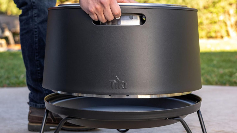 Close-up of a man assembling a Tiki Smokeless Fire Pit