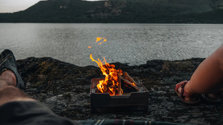 A fire burning by a lake in the Wolf and Grizzly Fire Safe