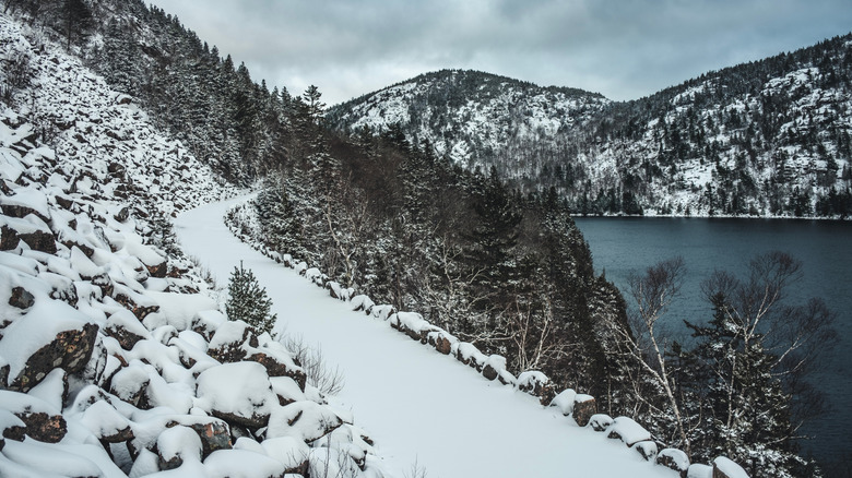 A snowy trail with a lake and mountains in the distance at Acadia National Park