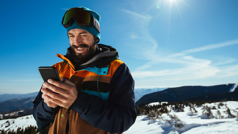Skiier using cell phone outside 