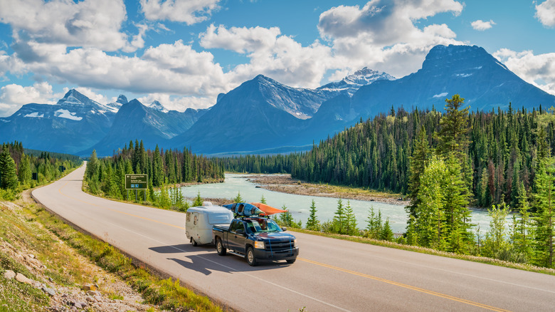 Camper van and truck driving past mountain range