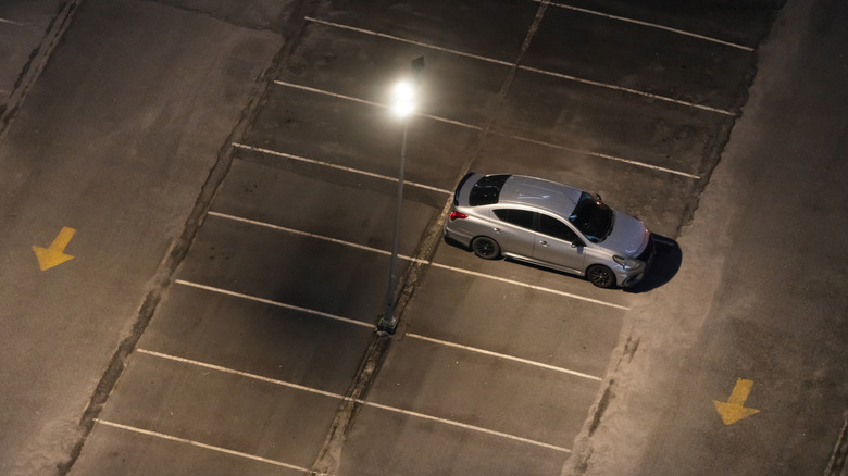 Car in empty parking lot late at night