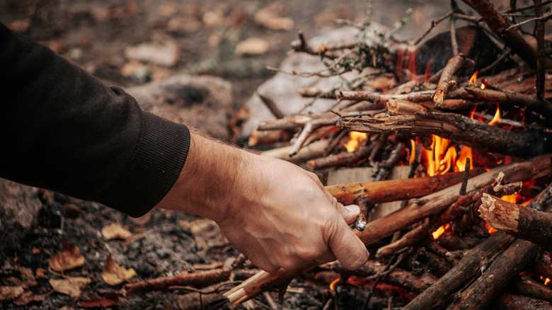 Adding small sticks to campfire