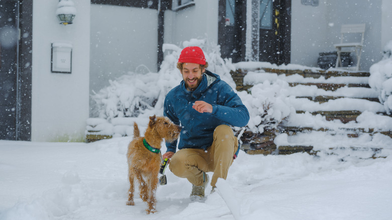 man smiles at dog outside after snowfall