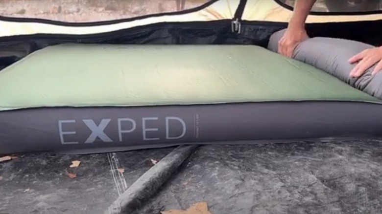rolling up an Exped MegaMat in a tent