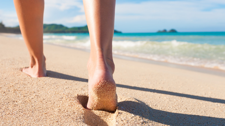 Person's sandy feet walking on a beach