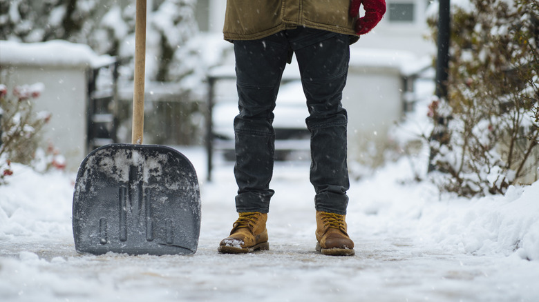 Person pauses while shoveling driveway