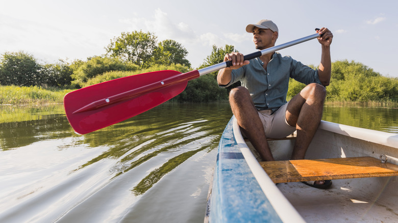 Man paddling a canoe in a marsh