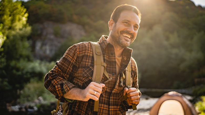 male hiker with backpack and tent in background
