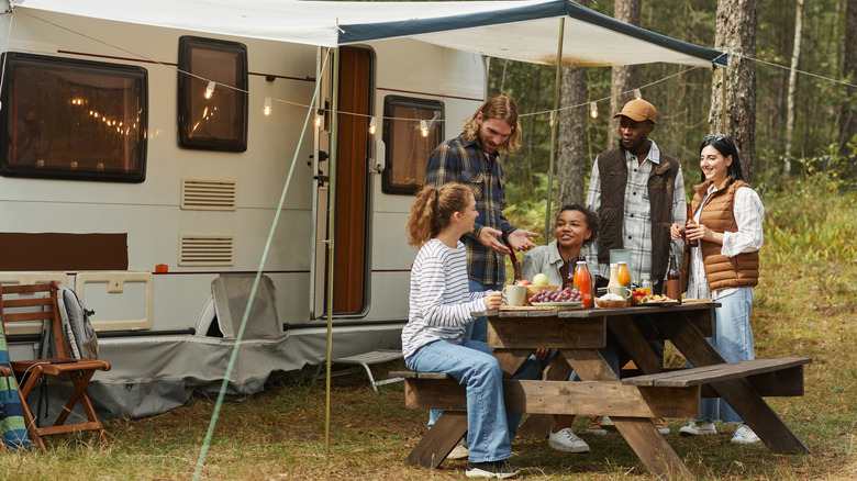 Group of campers sitting by food in front of RV