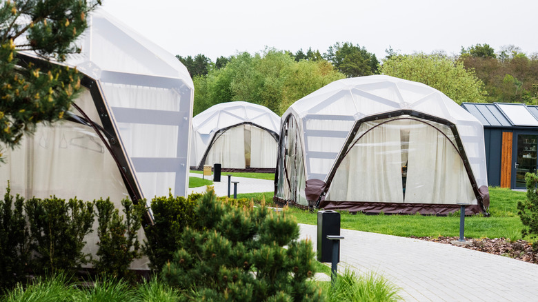 A series of geodesic dome tents, set up along a paved trail