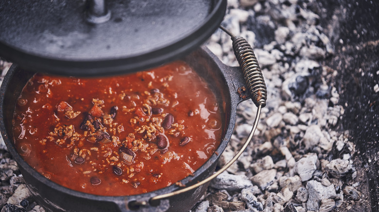 Cooking chili in a Dutch oven over campfire coals