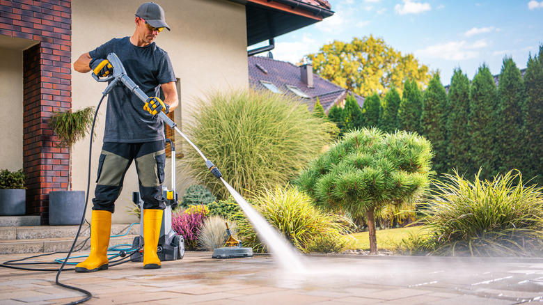 A homeowner pressure washes his driveway