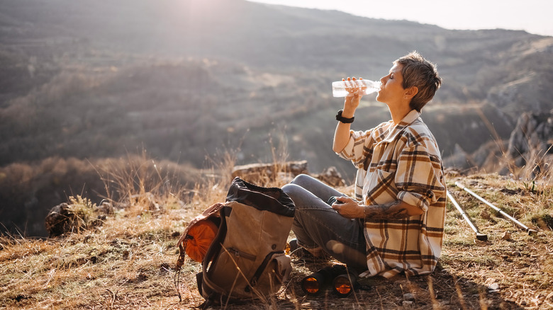 Woman drinks water while hiking