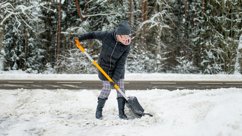 Woman shovels snow off driveway