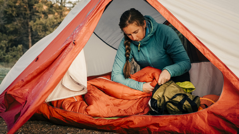Woman packing her gear inside tent