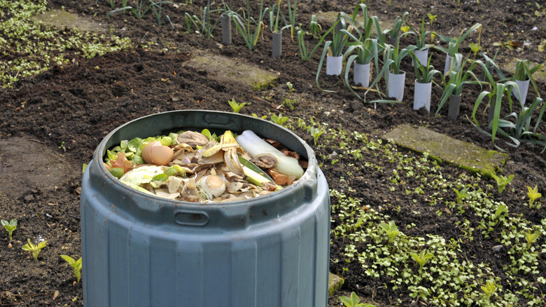 Full blue composter in a garden.