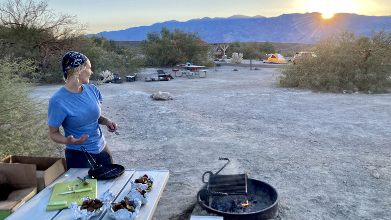 a woman cooks dinner while camping in Death Valley National Park at sunset
