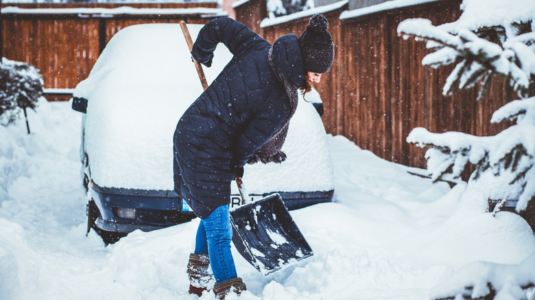 Woman shoveling snow piled in her driveway