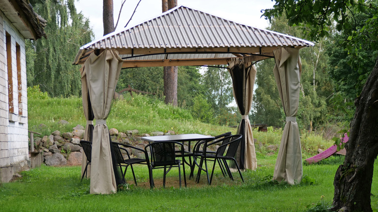 A simple modern gazebo with a table and chairs underneath