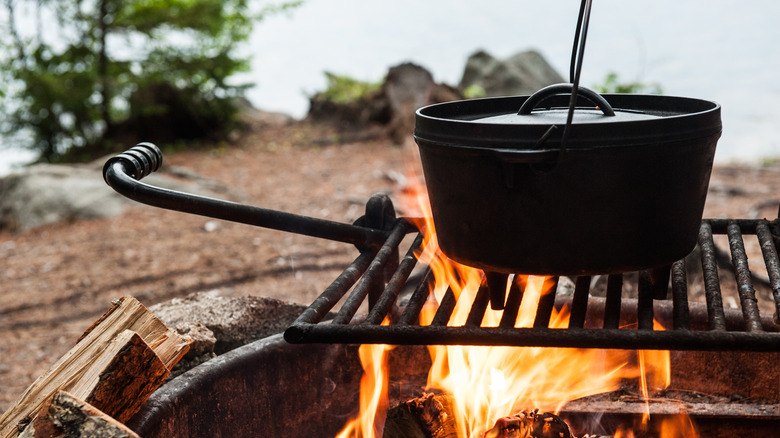 A black cooking pot on a grate over open fire