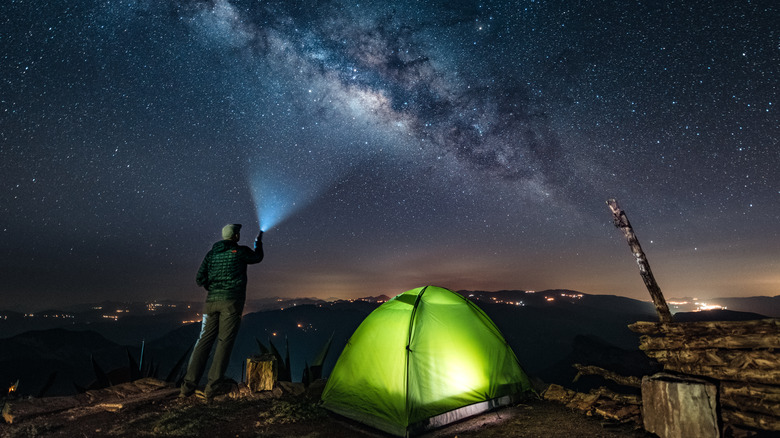Camper using flashlight while stargazing