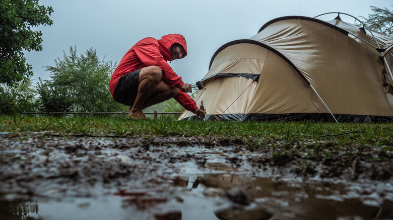 Camper next to tent in rain