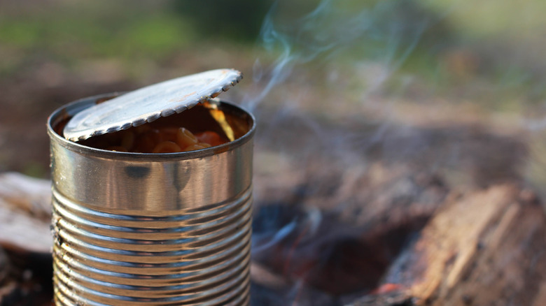 Tin can full of beans being heated on campfire