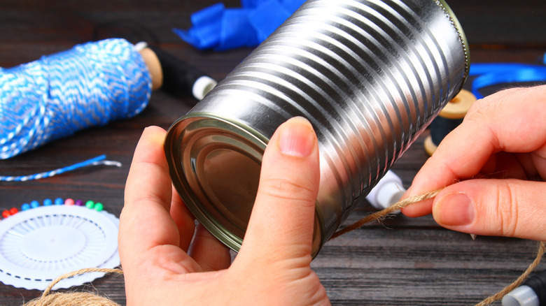 A person wrapping string around a tin can