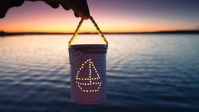 Tin can lantern with sailboat design being held by string