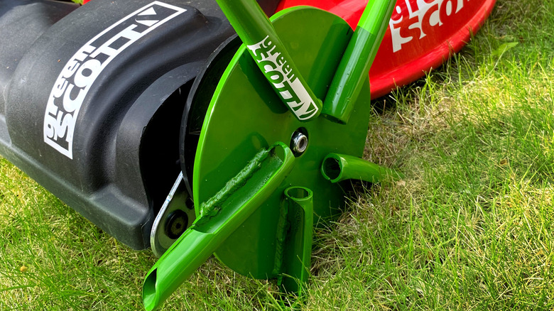 Green Scott core aerator wheel attached to the front wheel of a lawn mower