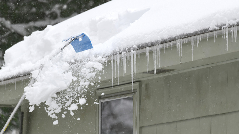 Metal roof rake removing snow from roof