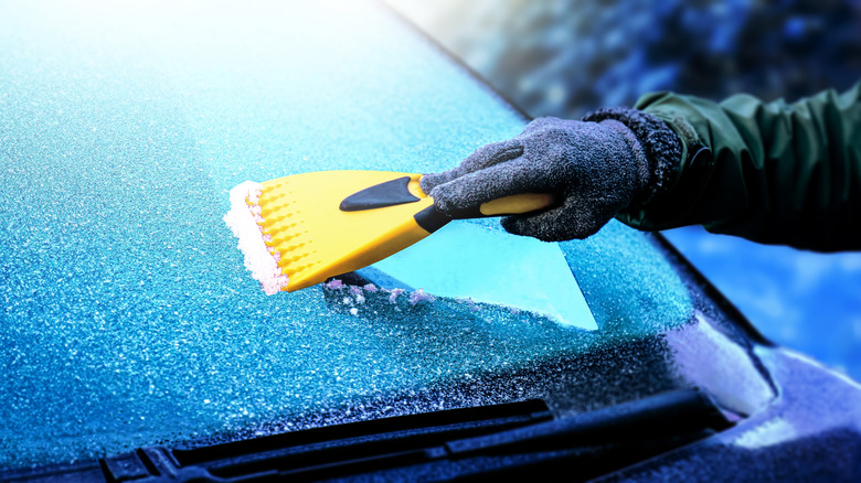 Person scraping ice from their windshield