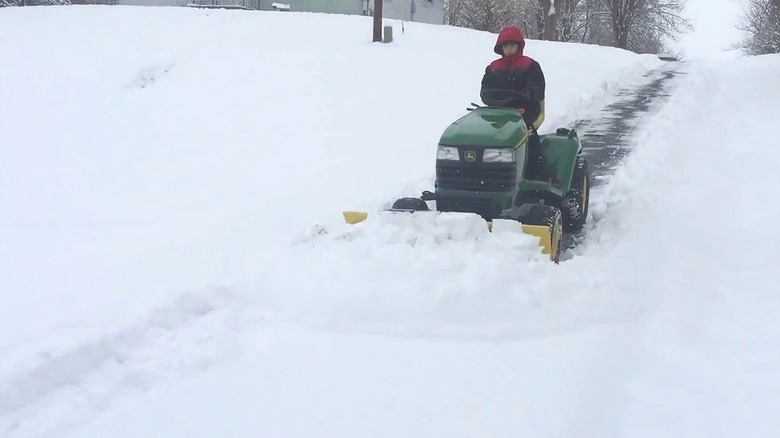 Person plowing driveway with tractor plow
