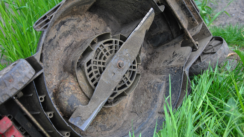 An overturned lawn mower exposing a sharp blade