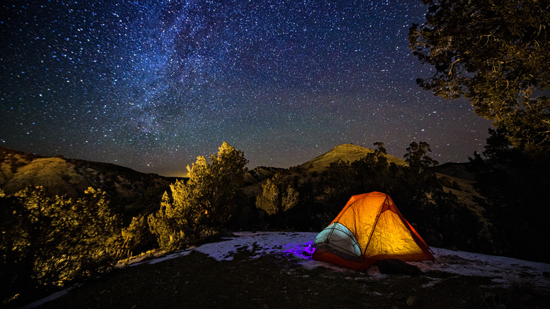 Camping tent under star-filled night sky 