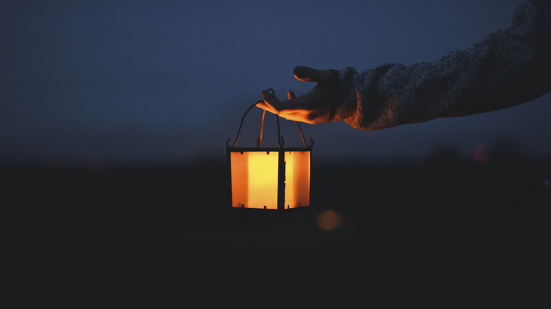 person holds a lantern after dark