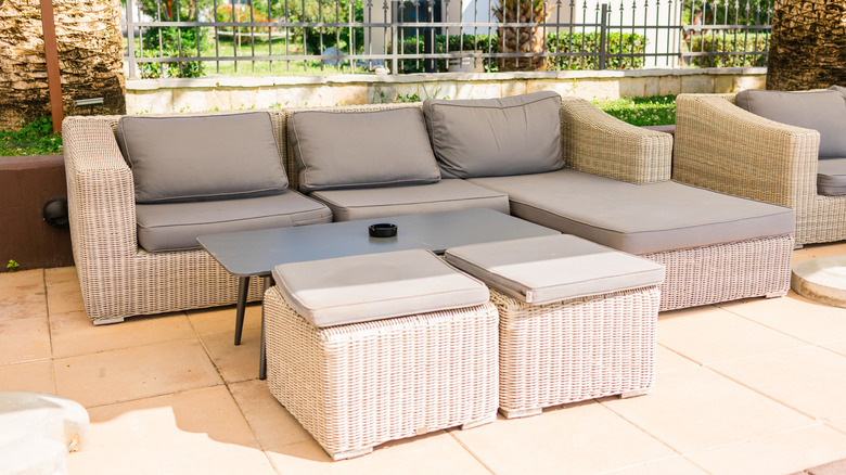 A modern rattan outdoor sofa with stools and a table