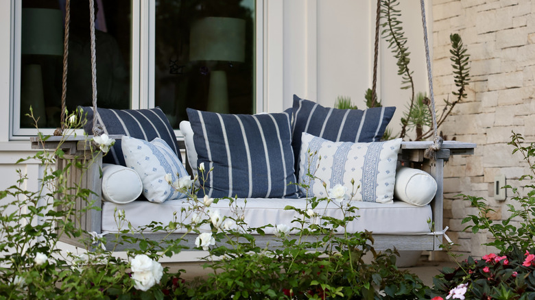 A porch swing with blue and white-striped cushions