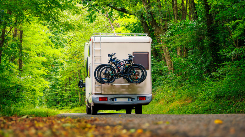 A motorhome traveling down a wooded country road