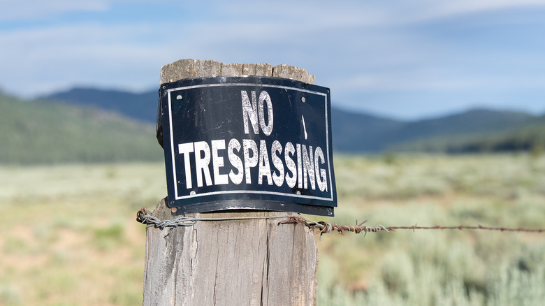 A "no trespassing" sign on a fence post