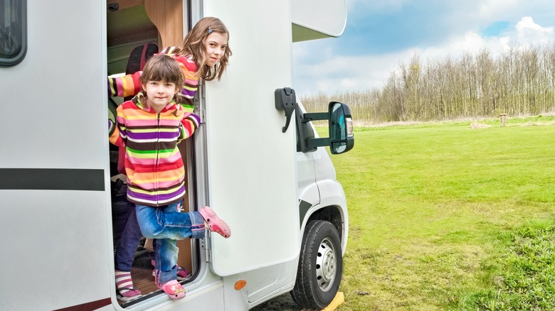 Two young children standing in the doorway of an RV