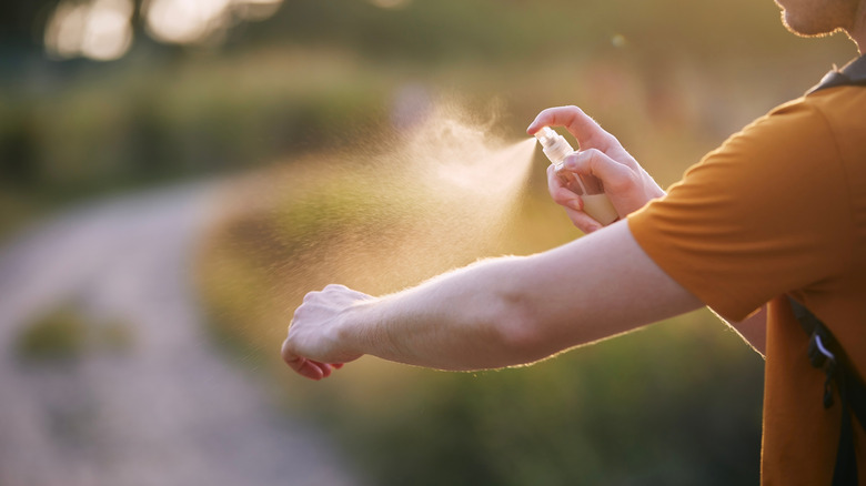 Person spraying bug repellent on arm