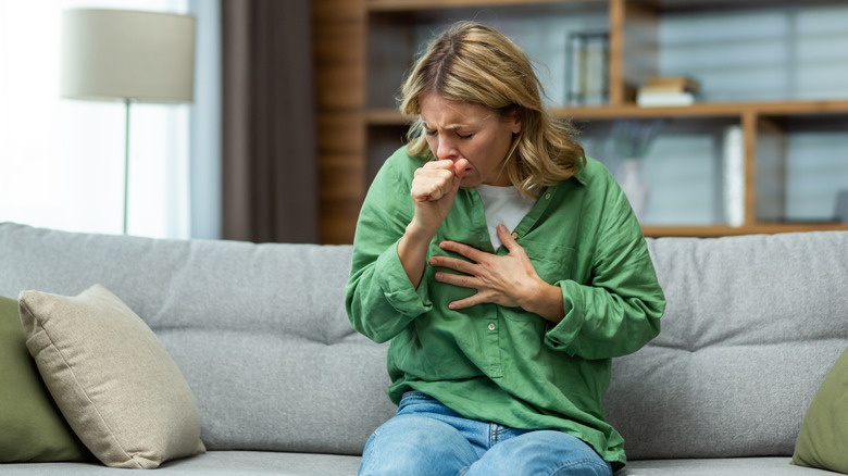 Seated woman coughing and holding chest